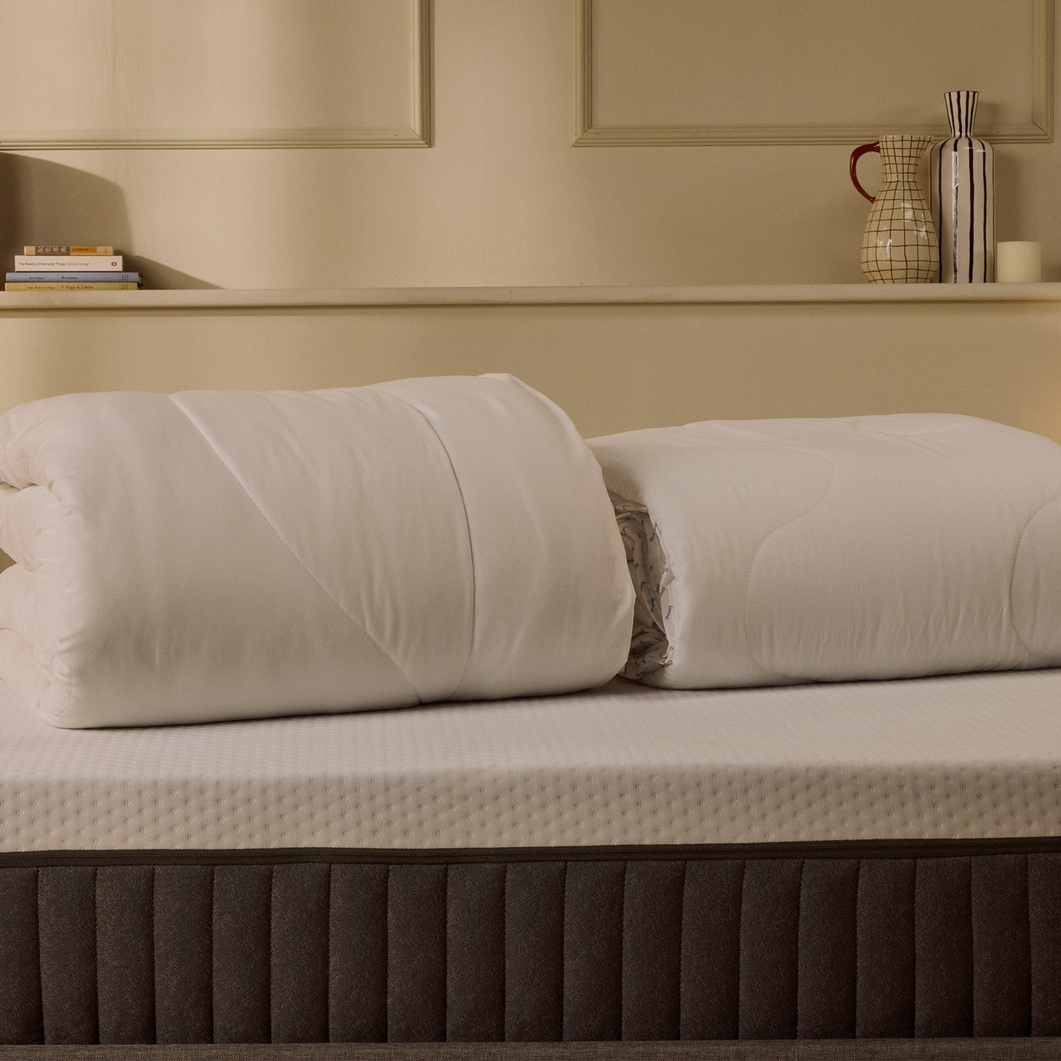 Two folded duvets on top of a mattress.