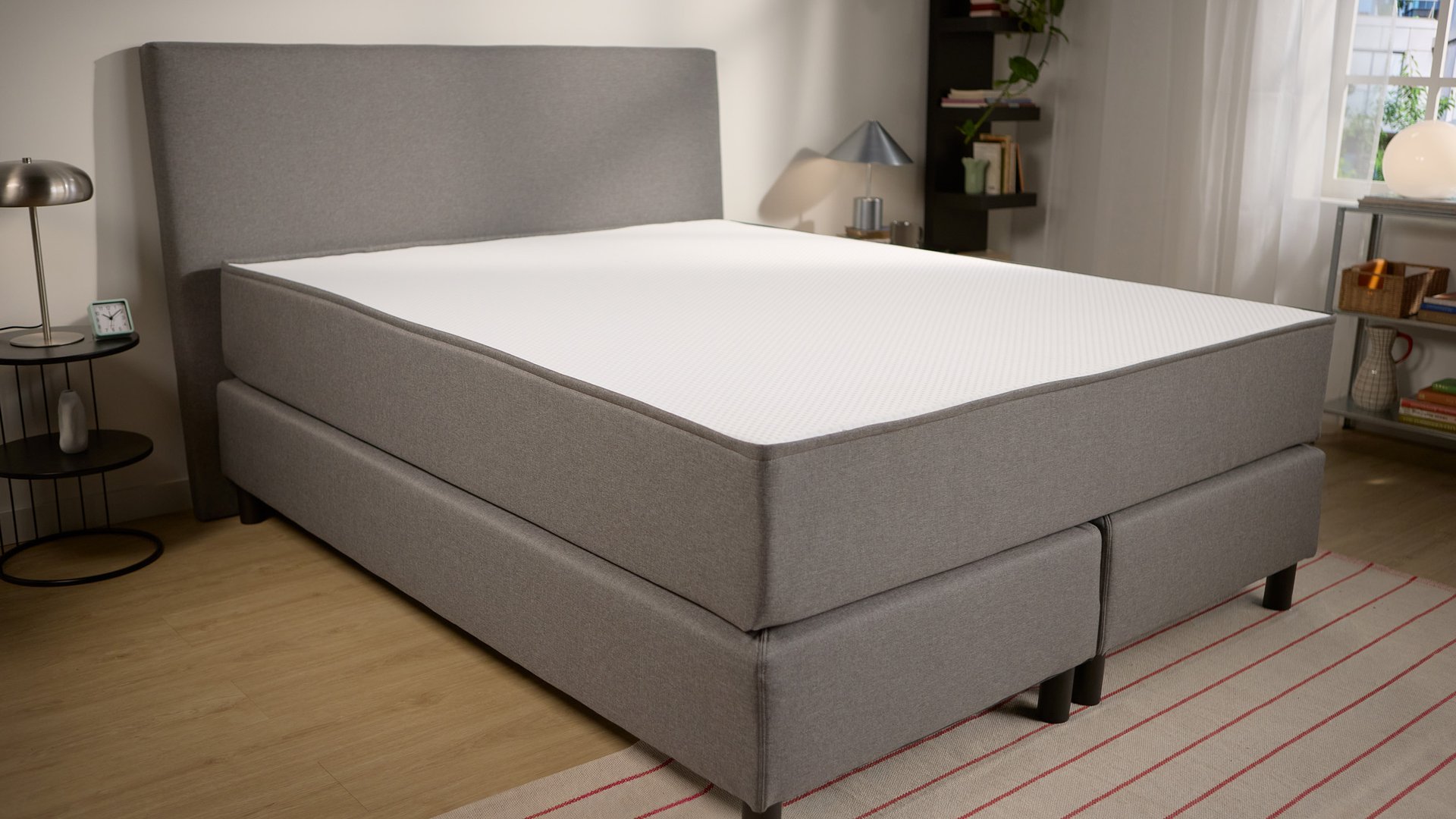 Schrägansicht, die das gepolsterte Untergestell, die Tiefe des Kopfteils und zwei mittige Stützfüße für mehr Stabilität zeigt.