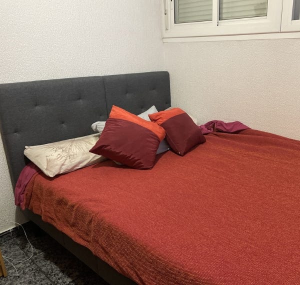 cama tapizada emma con sabanas rojas y unas almohadas