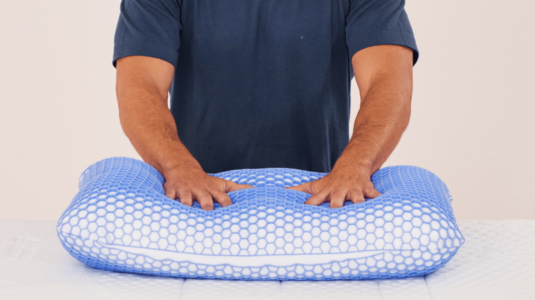 Homme portant une chemise sombre, appuyant doucement ses mains sur un oreiller avec une grille en forme de nid d’abeille bleue.