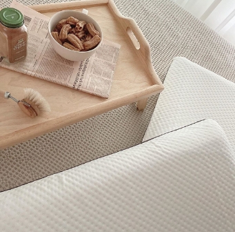 Houten dienblad met schaal met gedroogd fruit, borstel en fles op een Emma matras naast twee Emma Diamond kussens.