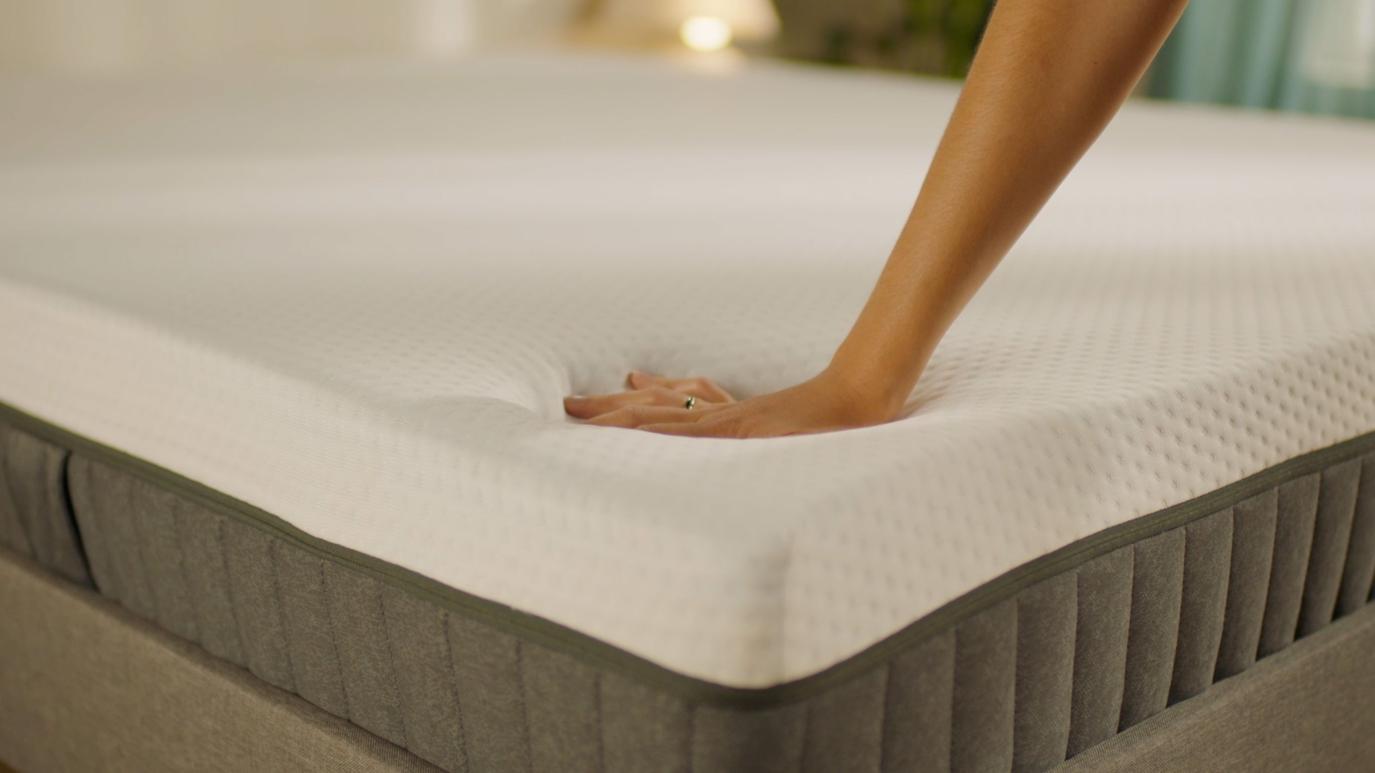 Person pressing the mattress surface to show its feel.