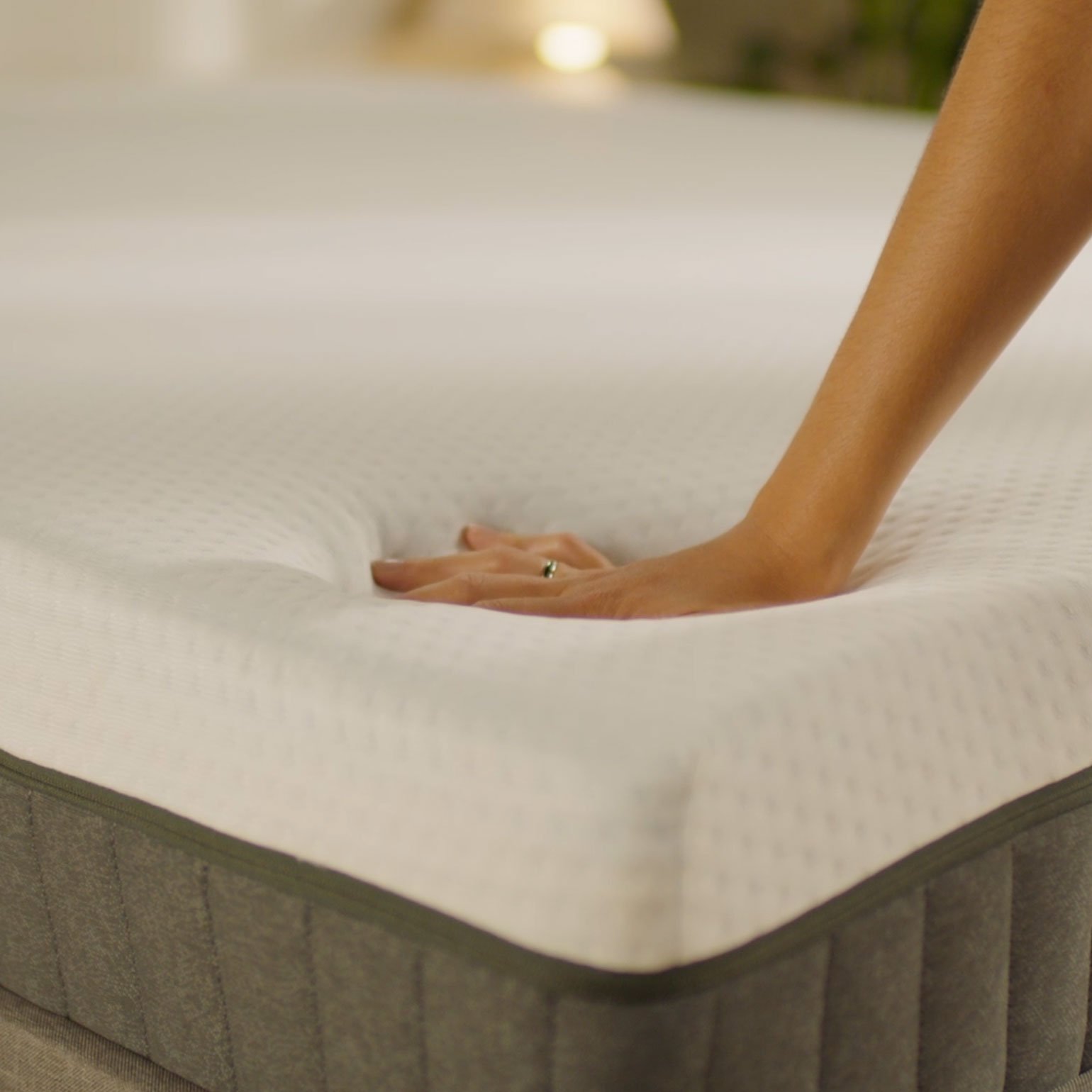 Hand pressing into the Emma Original Lite mattress surface, showing the softness and responsiveness of the cover.
