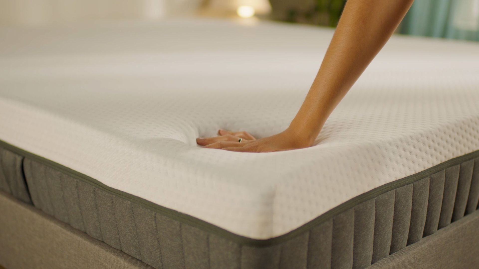 Person pressing the mattress surface to show its feel.