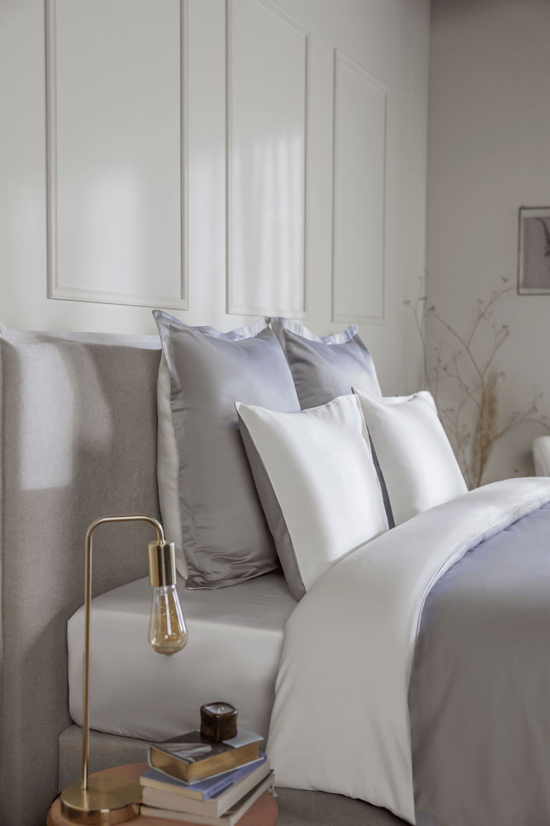 Elegante Emma Bettwäsche in Grau und Weiß auf einem gemachten Bett.