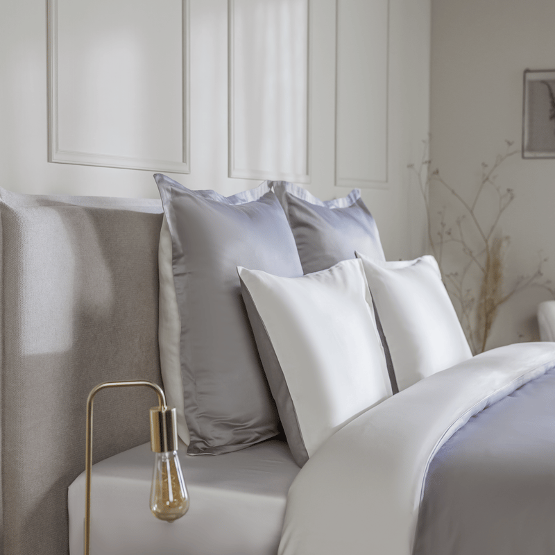 Elegante Emma Bettwäsche in Grau und Weiß auf einem gemachten Bett.