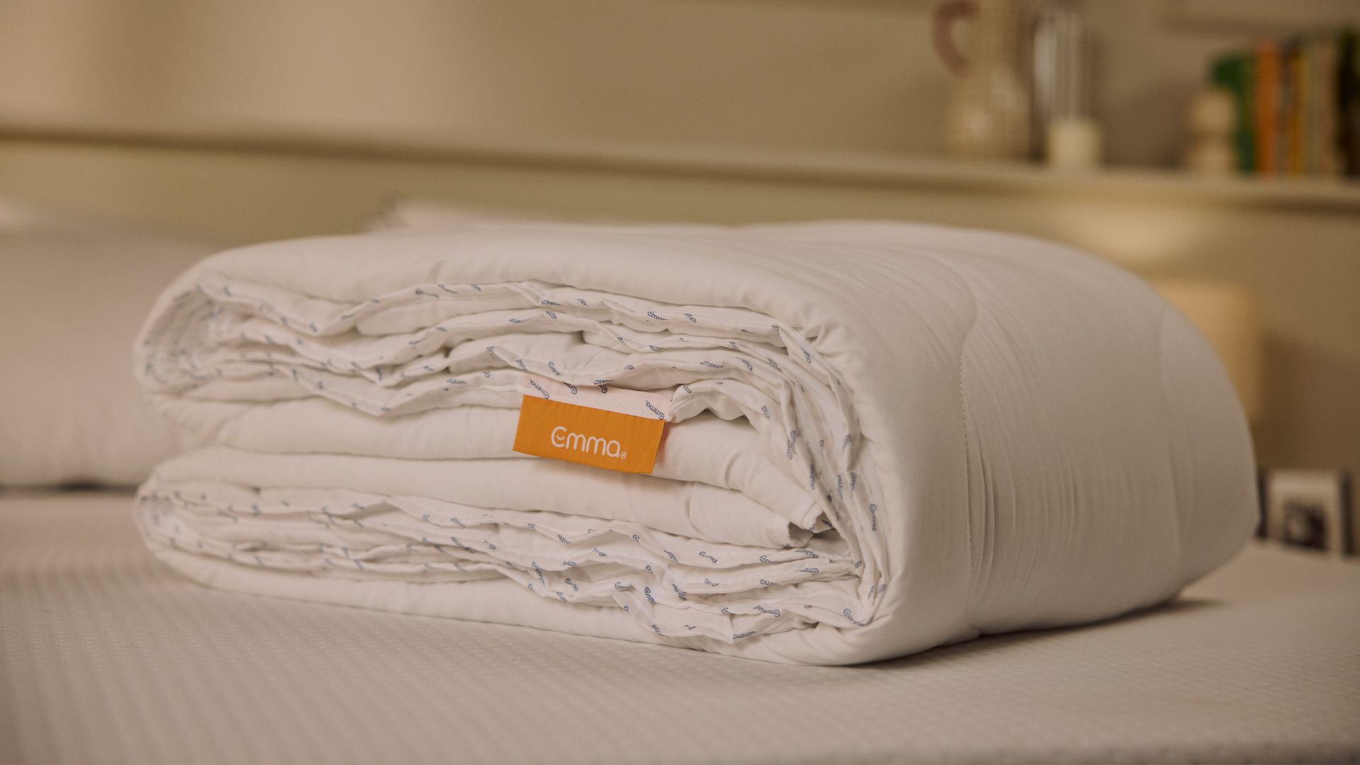Emma dekbed Lente/Zomer variant, opgerold en liggend op een bed in een neutrale slaapkameromgeving.