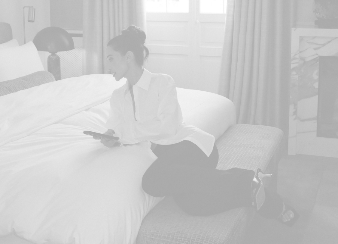 Roxie Nafousi laying on a bed, dressed in a white robe.