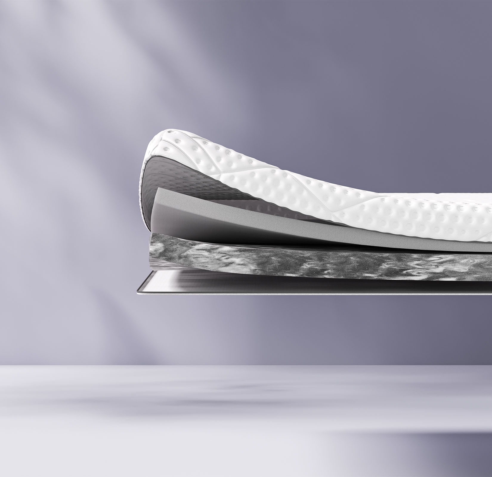 Coupe transversale d’un surmatelas montrant plusieurs couches, dont une couche supérieure texturée blanche et des couches intermédiaires bleues et jaunes. Le surmatelas porte l’inscription « Emma » sur le côté.