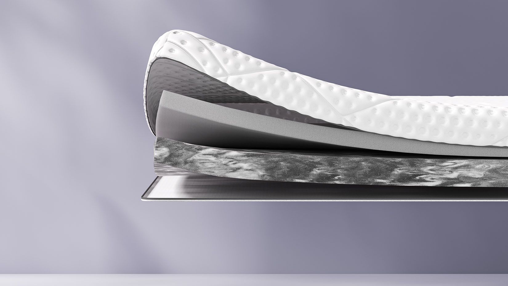 Coupe transversale d’un surmatelas montrant plusieurs couches, dont une couche supérieure texturée blanche et des couches intermédiaires bleues et jaunes. Le surmatelas porte l’inscription « Emma » sur le côté.