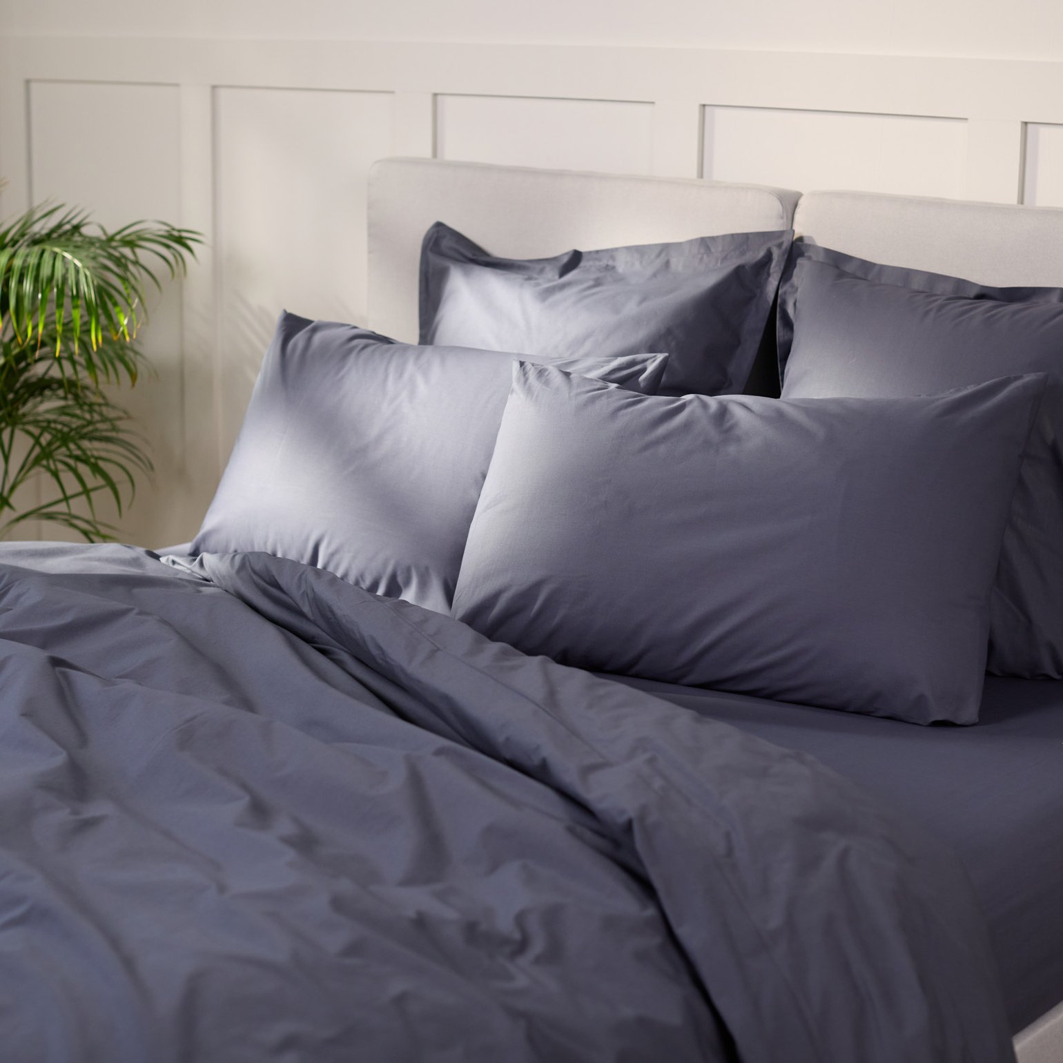 Uma cama com roupa de cama em cinza