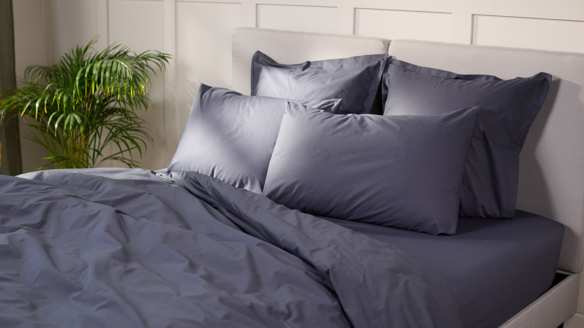 Uma cama com roupa de cama em cinza