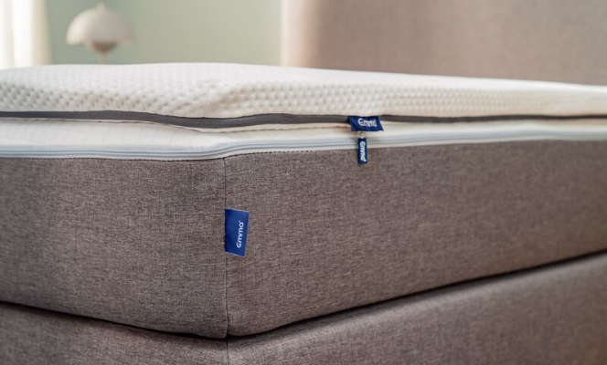 Close-up van de Emma Flip Topper met zichtbaar Emma-label, textuur en ritssluiting—omkeerbare topper met ademende hoes en dubbele schuimlagen voor zacht of stevig comfort.