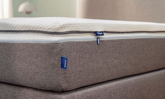 Close-up van de Emma Flip Topper met zichtbaar Emma-label, textuur en ritssluiting—omkeerbare topper met ademende hoes en dubbele schuimlagen voor zacht of stevig comfort.