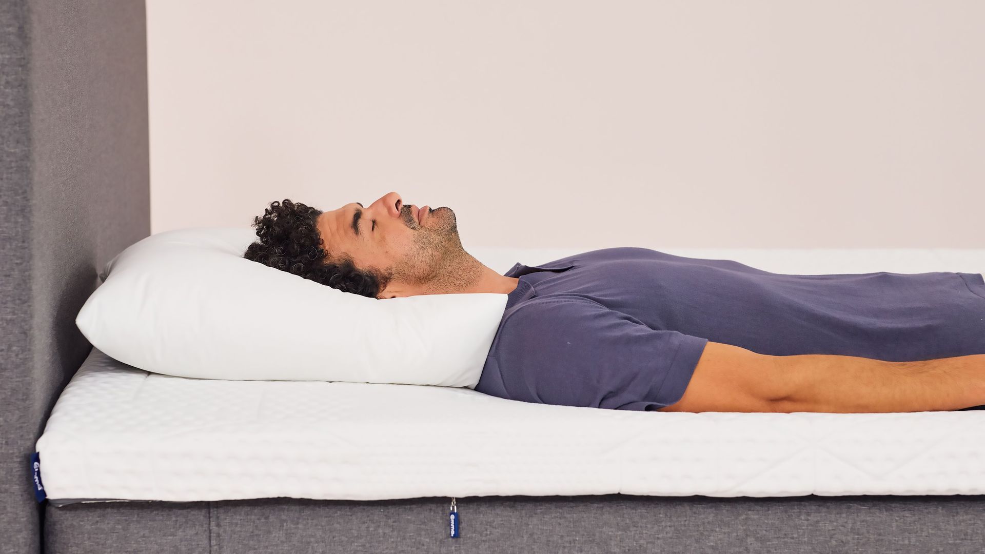 Hombre durmiendo sobre almohada microfibra blanca sobre colchón emma