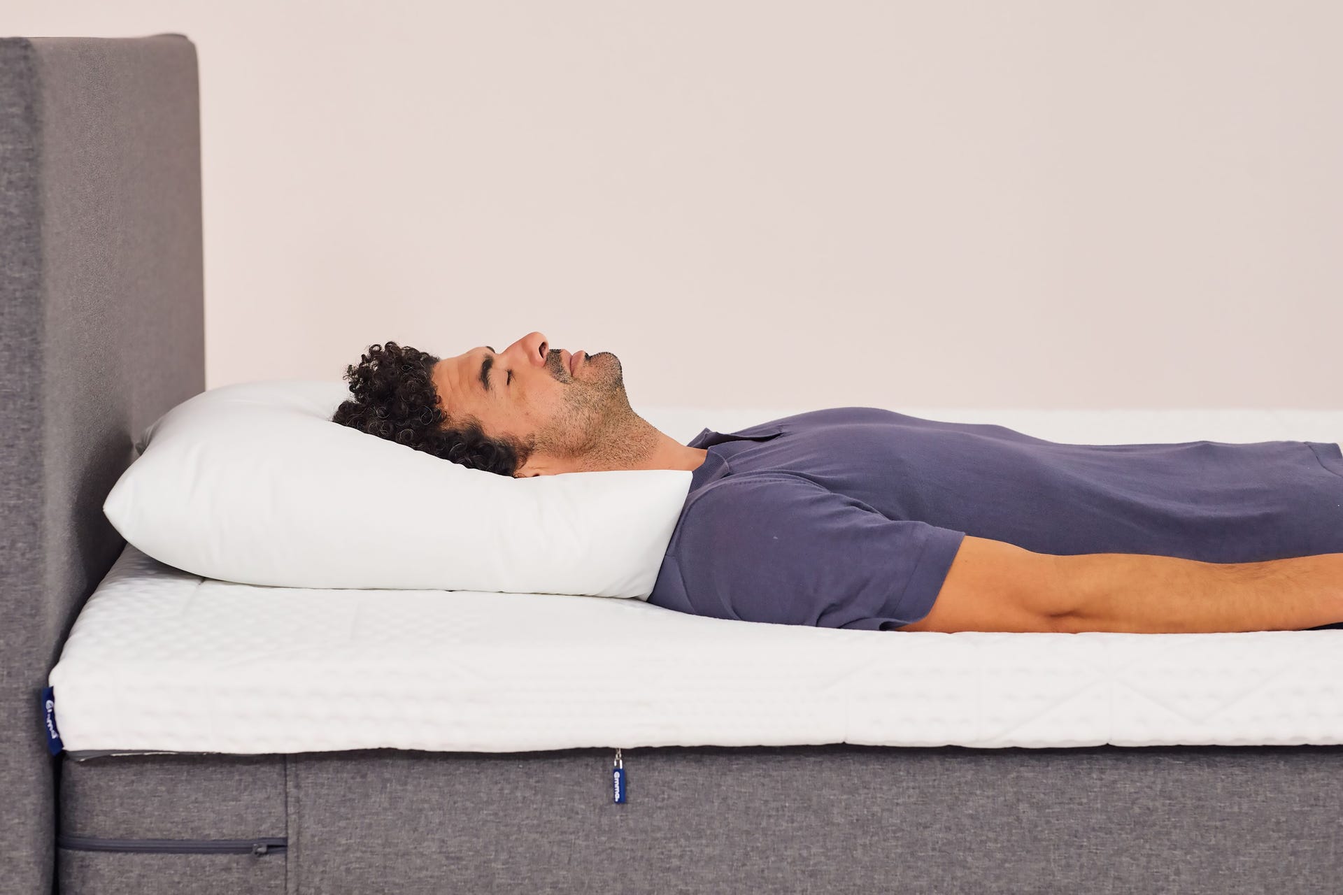 Hombre durmiendo sobre almohada microfibra blanca sobre colchón emma