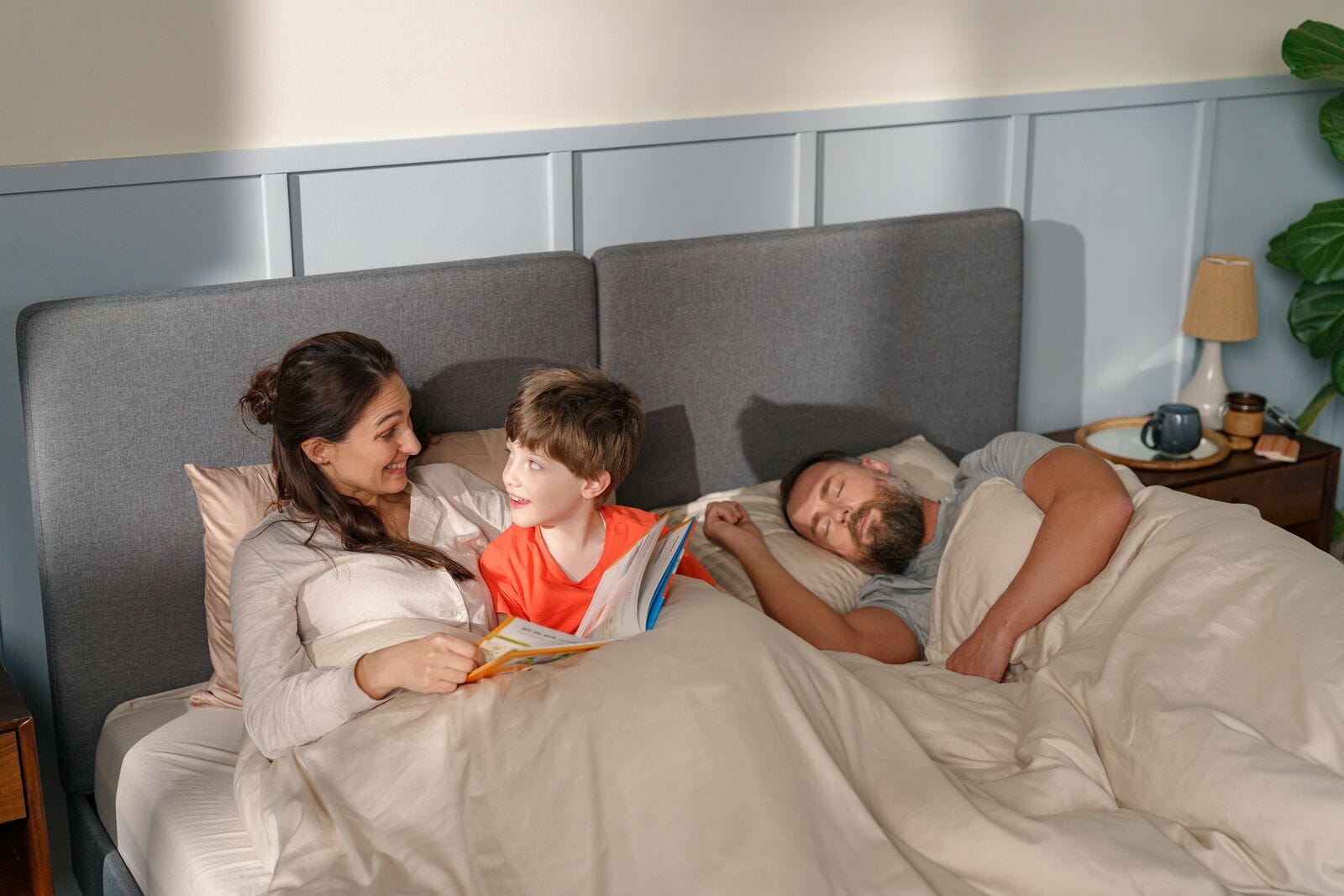pareja en la cama con un niño leyendo un cuento antes de ir a dormir