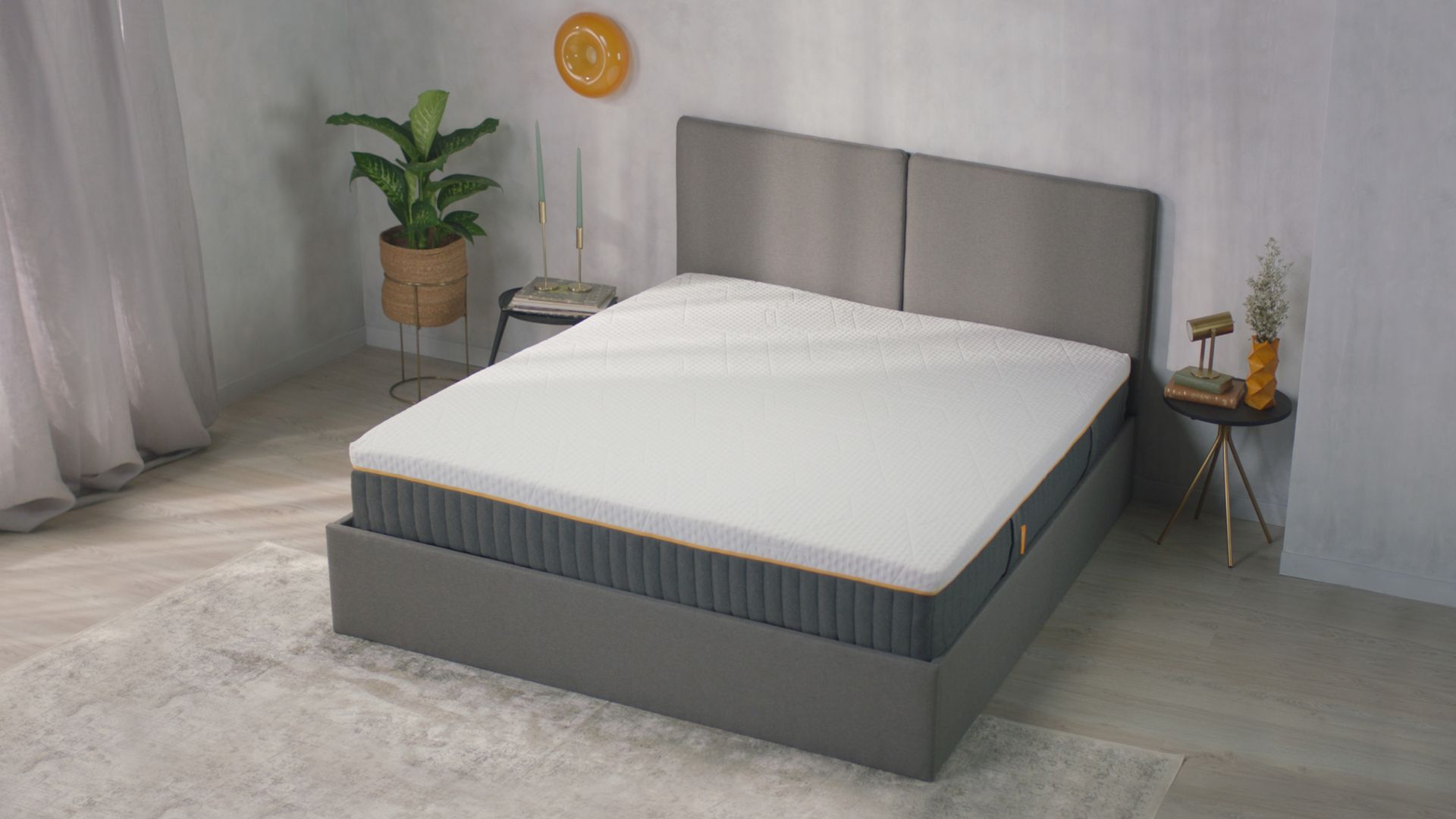 Letto con testiera e base grigia in stanza chiara con pianta e decorazioni