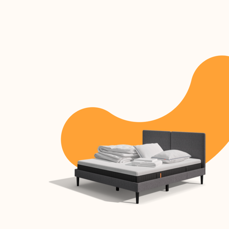 Lit moderne avec tête de lit grise et pieds noirs, recouvert de draps blancs. Deux oreillers blancs et une pile de linge plié sont posés sur le matelas. Arrière-plan beige avec une forme orange abstraite.