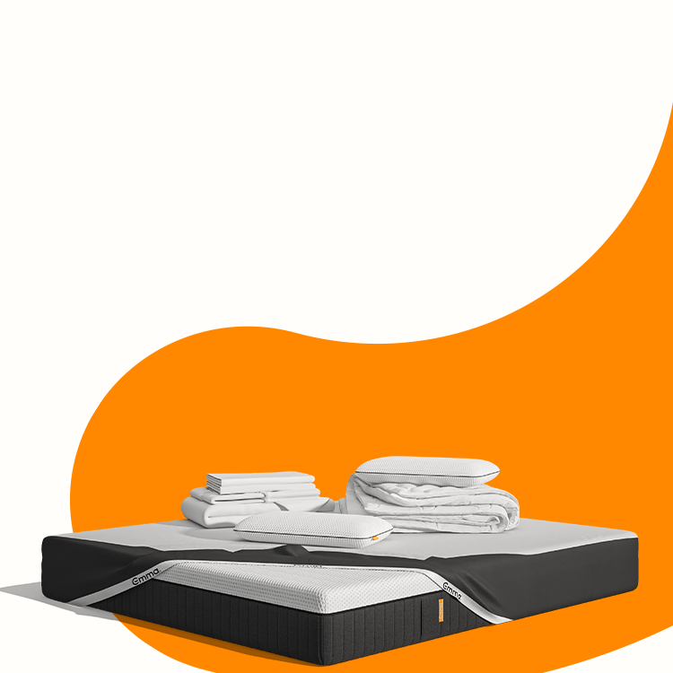 Lit moderne avec tête de lit grise et pieds noirs, recouvert de draps blancs. Deux oreillers blancs et une pile de linge plié sont posés sur le matelas. Arrière-plan beige avec une forme orange abstraite.