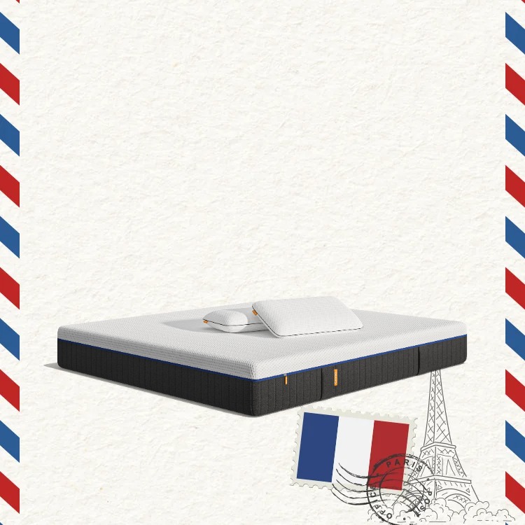 Lit moderne avec tête de lit grise et pieds noirs, recouvert de draps blancs. Deux oreillers blancs et une pile de linge plié sont posés sur le matelas. Arrière-plan beige avec une forme orange abstraite.