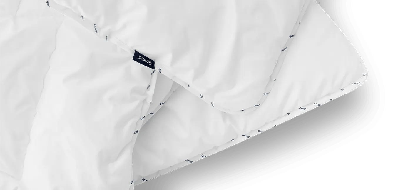 Close-up van het witte Emma Dekbed met herhaald logo langs de rand en zichtbaar label—licht.