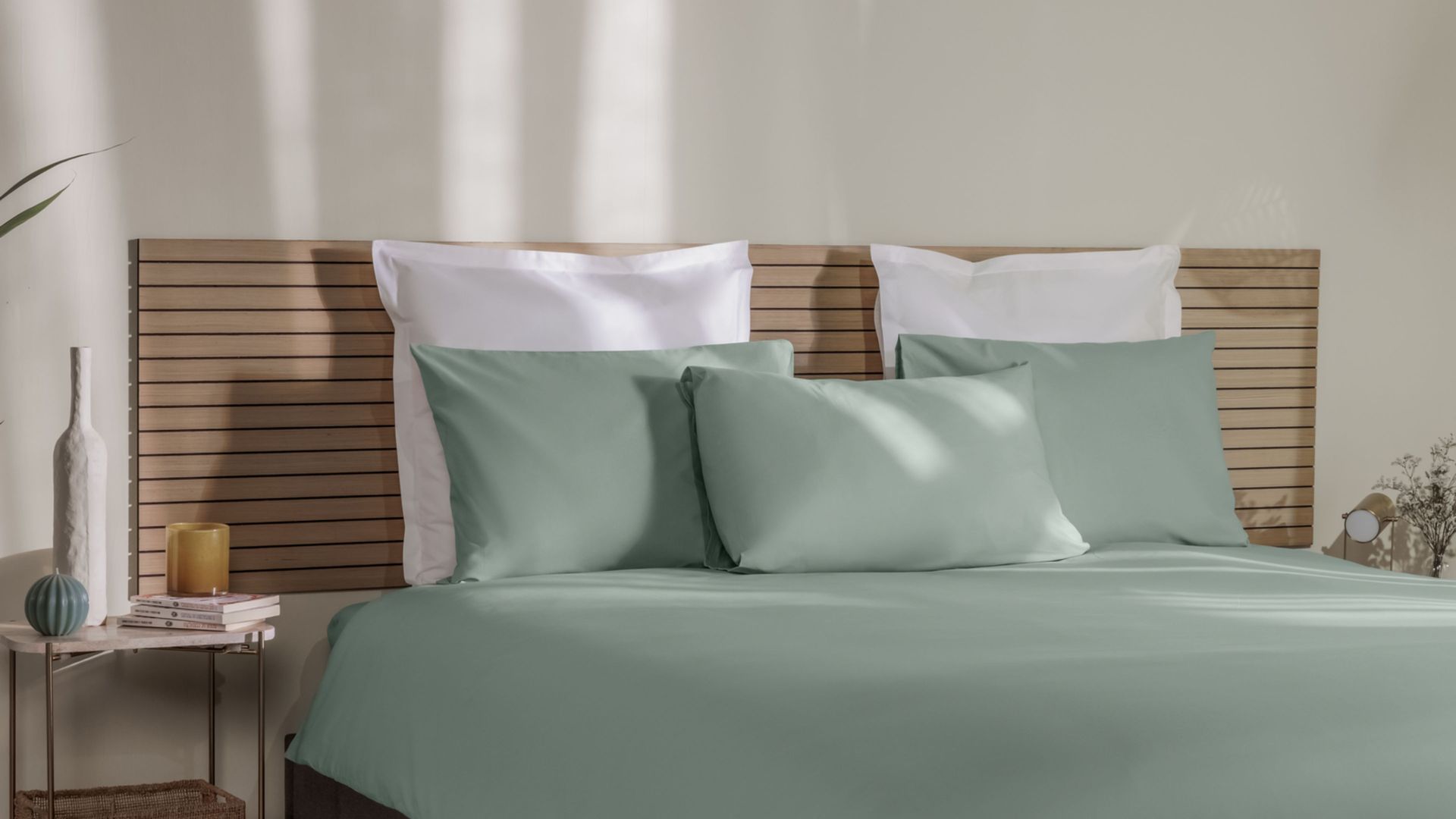 Letto con federe beige e bianche, coperta coordinata e testiera in legno.