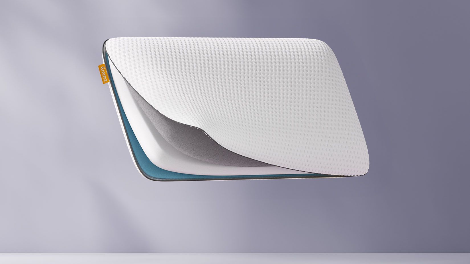 Oreiller flottant avec une grille en forme de nid d’abeille bleue, partiellement ouvert pour révéler le tissu intérieur, sur un fond violet clair.