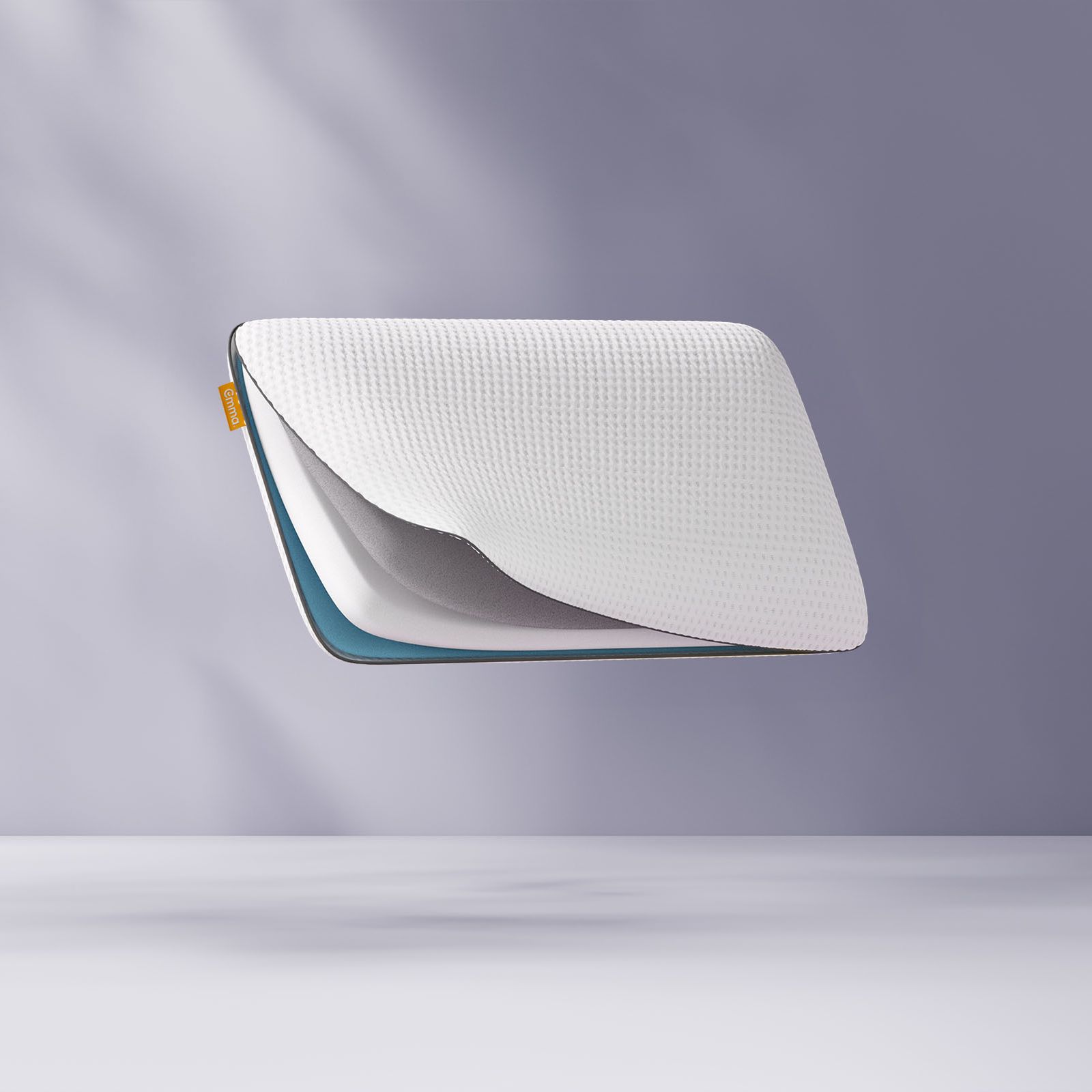 Oreiller flottant avec une grille en forme de nid d’abeille bleue, partiellement ouvert pour révéler le tissu intérieur, sur un fond violet clair.