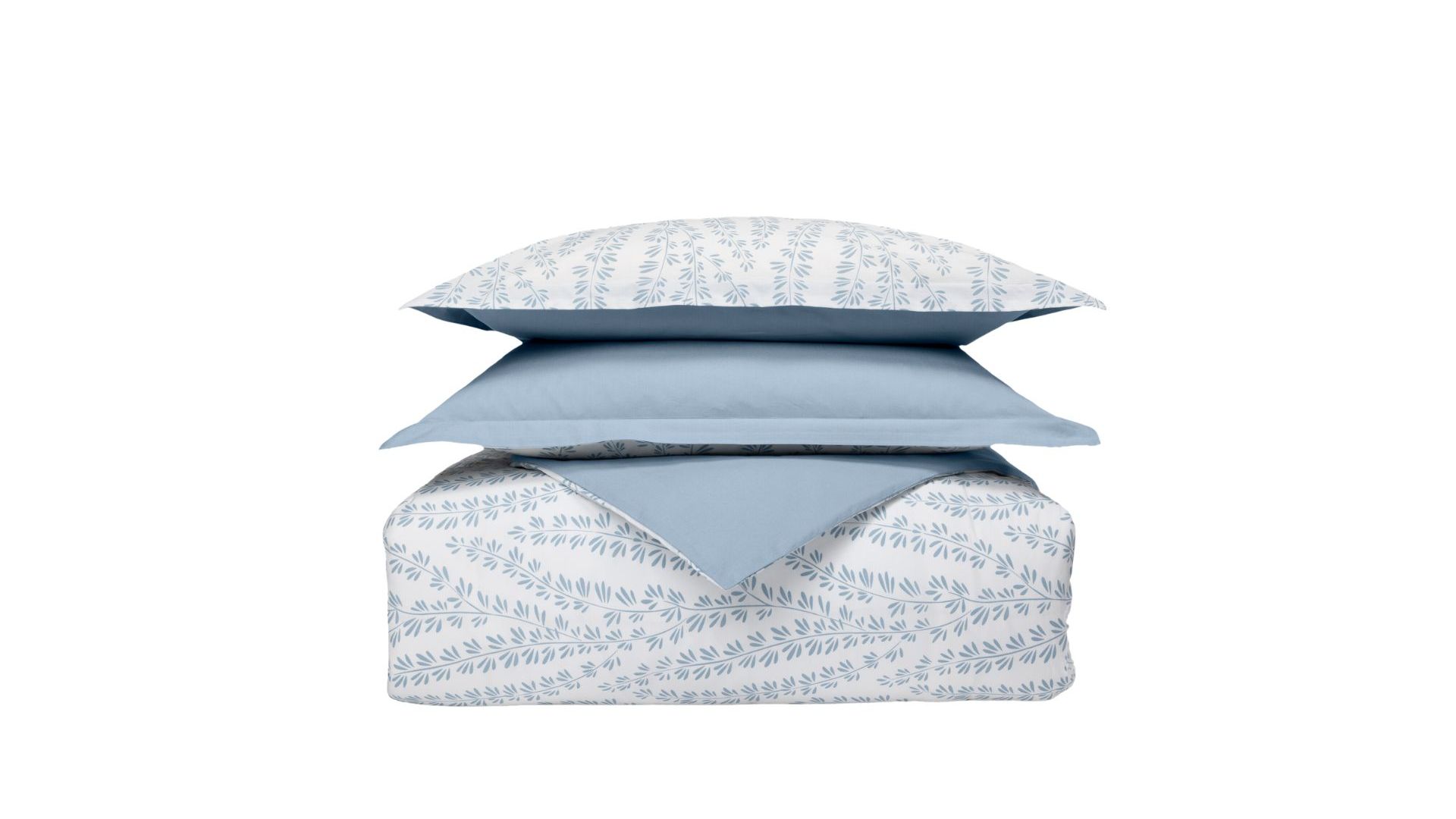 Set di biancheria impilato con cuscini e piumone a motivo foglia blu su sfondo bianco e un cuscino azzurro.