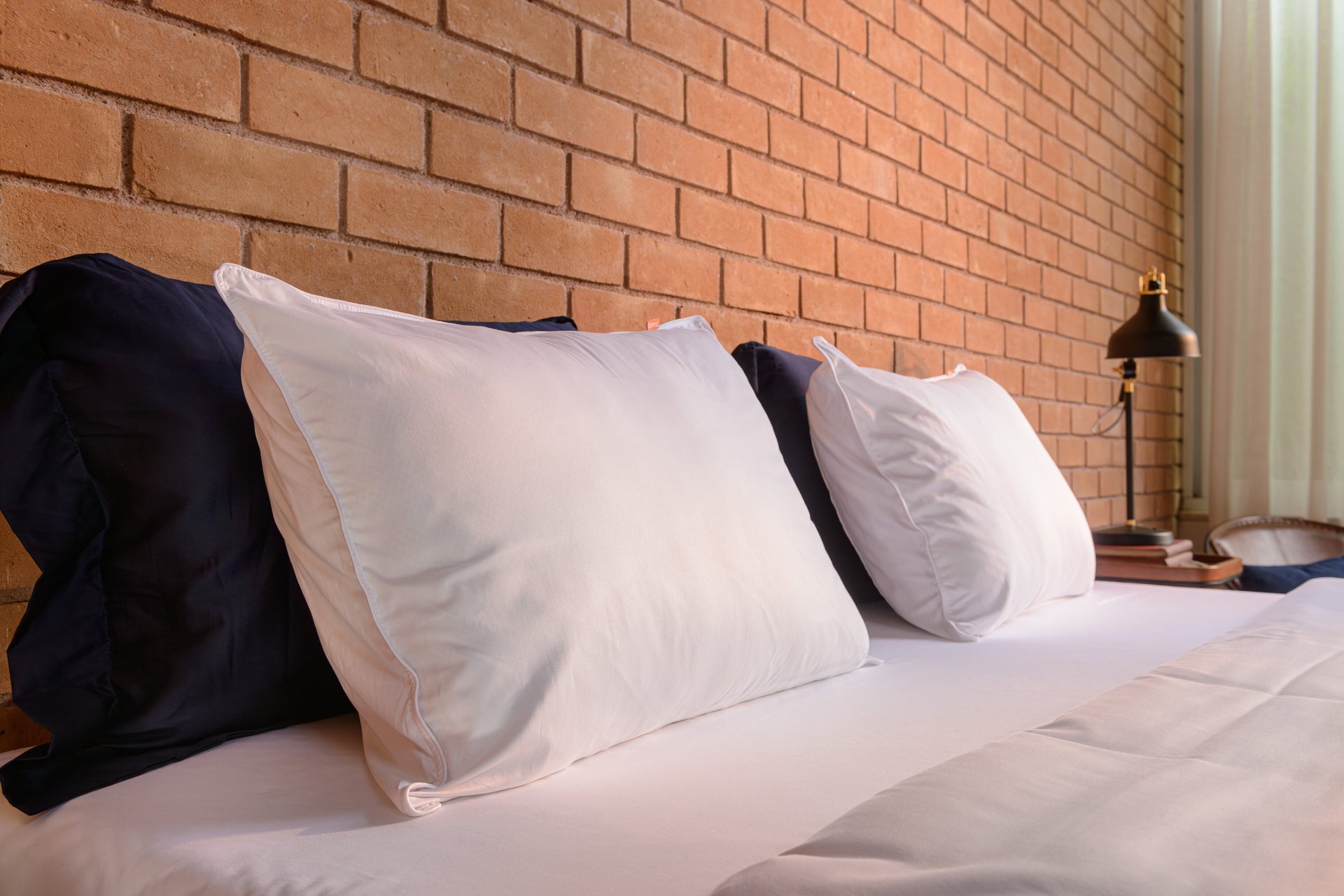 Travesseiros em cima de cama, encostados a uma parede