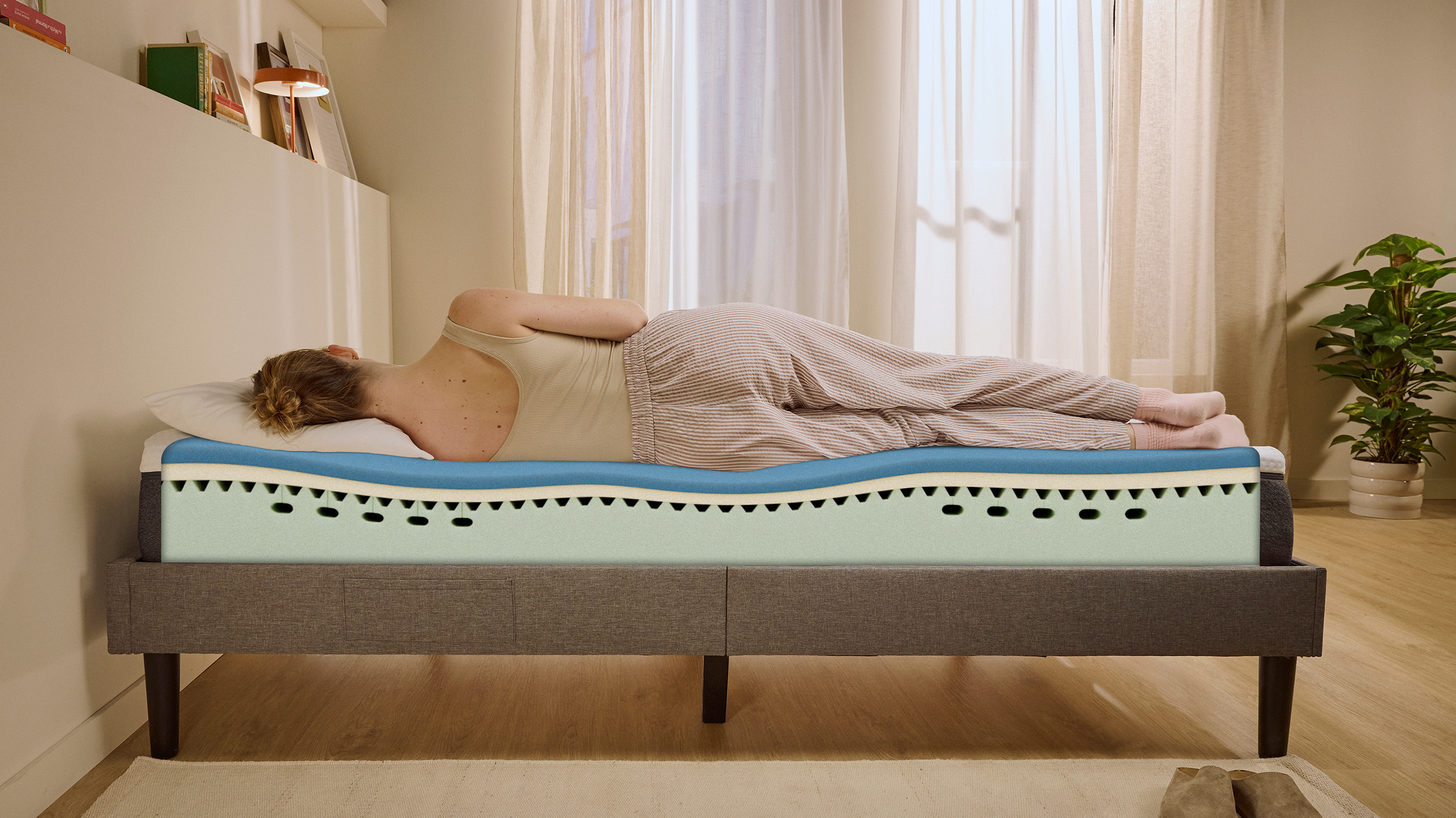 Person lying on their side on a white mattress in a relaxed sleeping position.