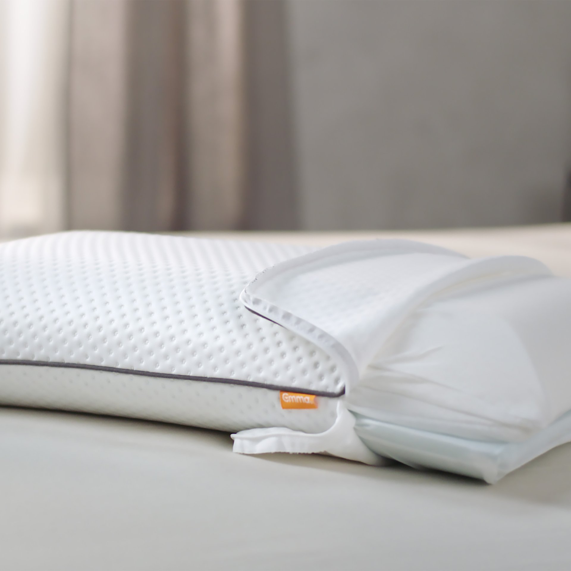 Cuscino bianco con superficie testurizzata e sistema a strati regolabili su letto chiaro