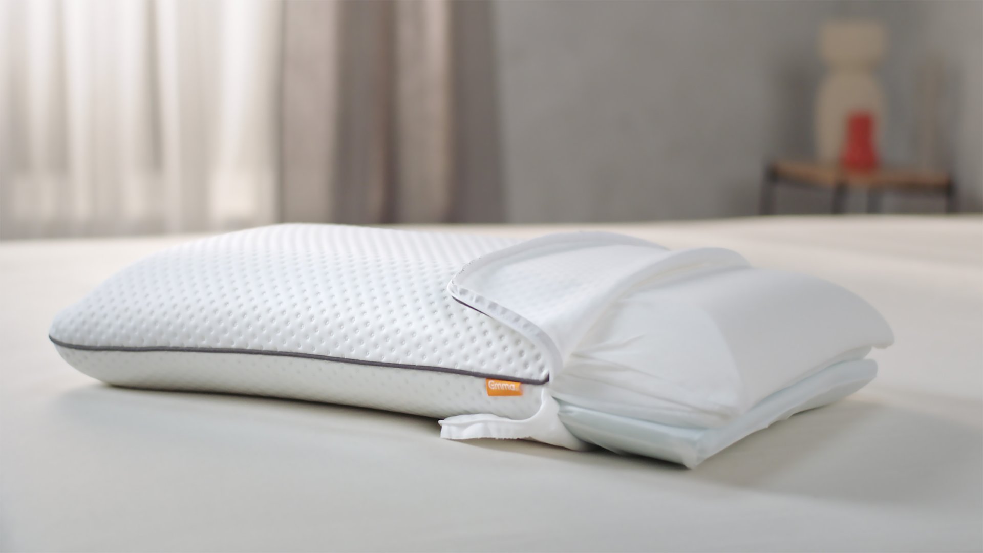Cuscino bianco con superficie testurizzata e sistema a strati regolabili su letto chiaro