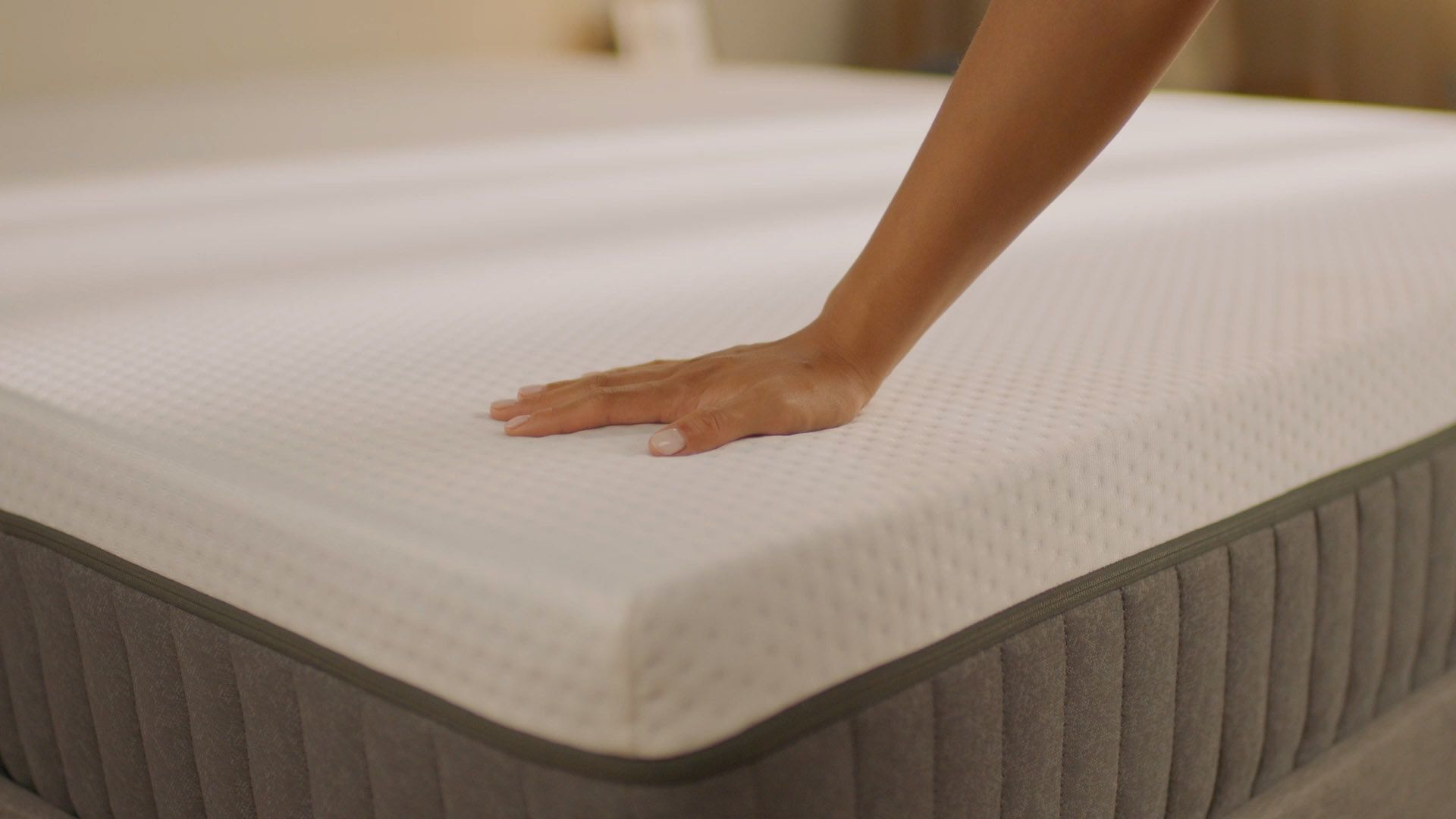 Main appuyant sur la surface d’un matelas en mousse haute densité pour montrer son soutien, sa souplesse et son confort ergonomique.