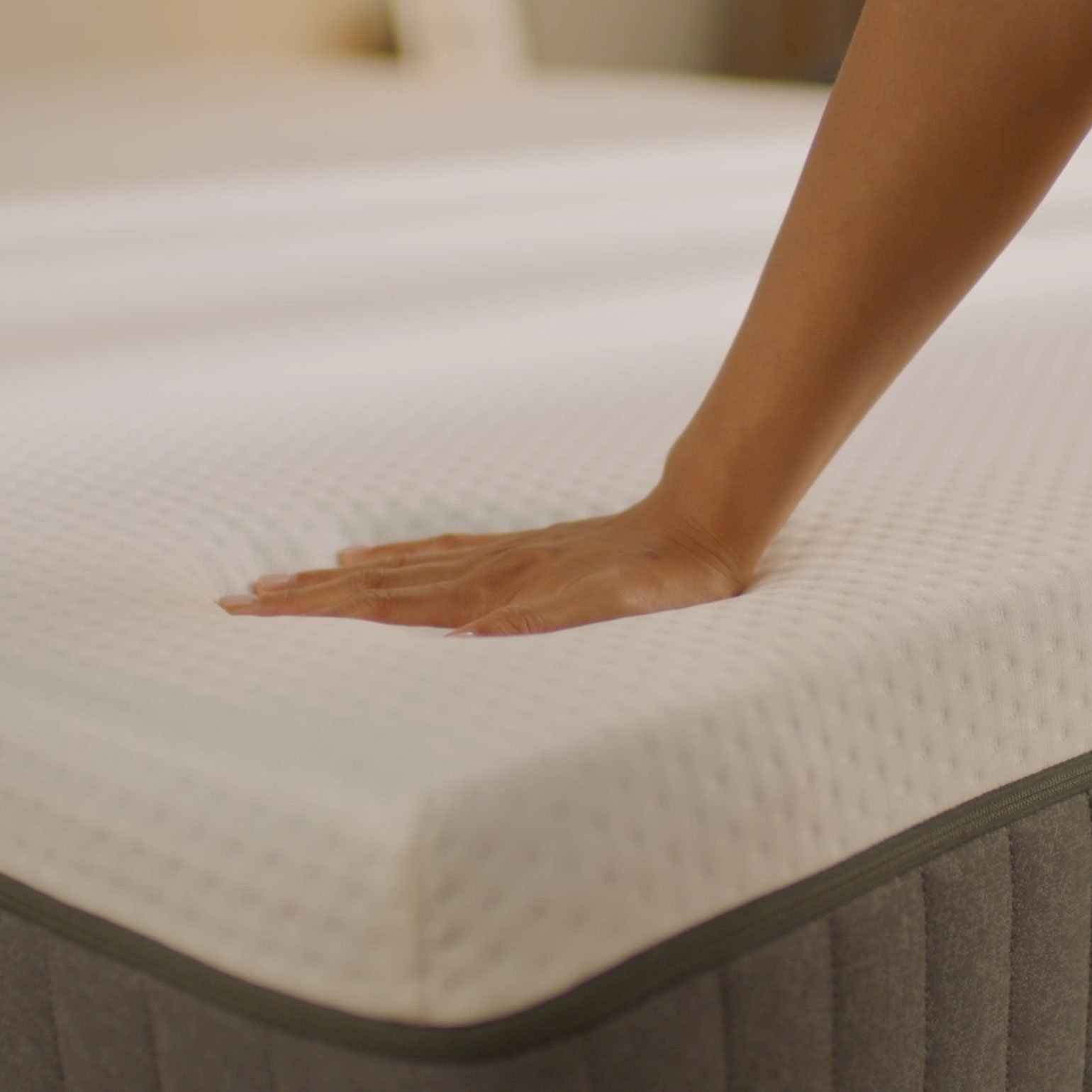 Person pressing the mattress surface to show its feel.