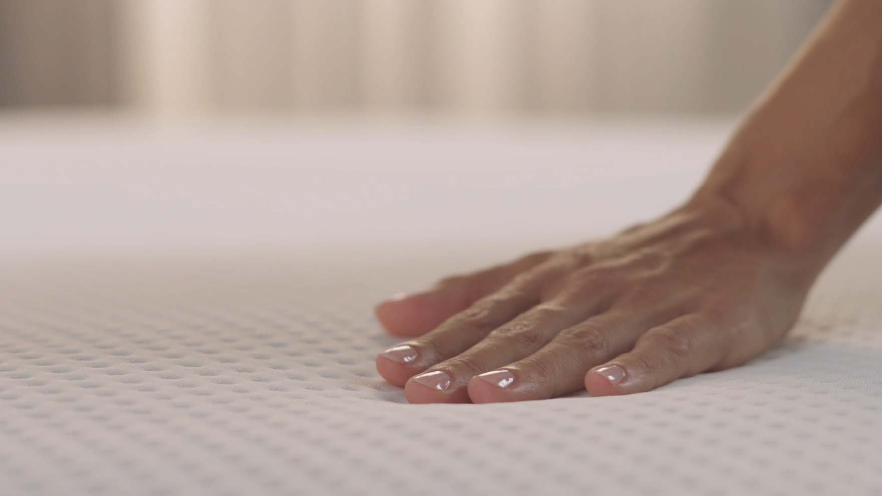 Mano tocando levemente colchón