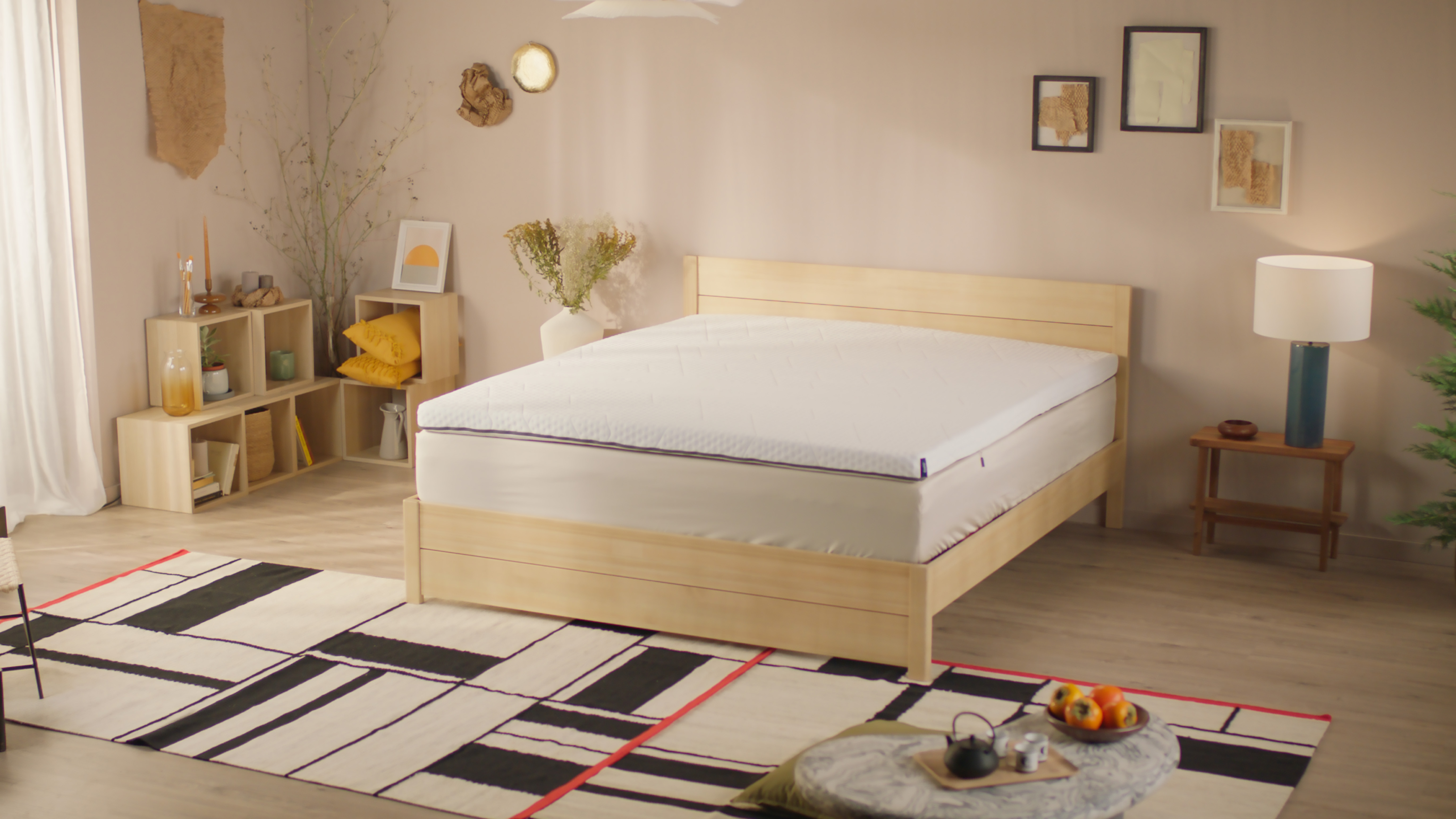 Uma imagem de um sobrecolchão Emma, posto sob um colchão e uma cama