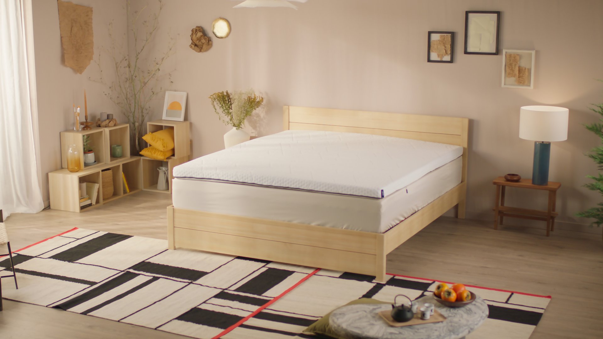 Uma imagem de um sobrecolchão Emma, posto sob um colchão e uma cama
