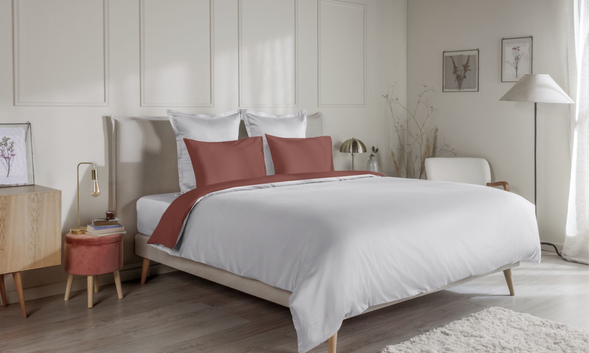 Letto con federe terracotta e coperta coordinata su biancheria bianca, in camera da letto dallo stile accogliente.