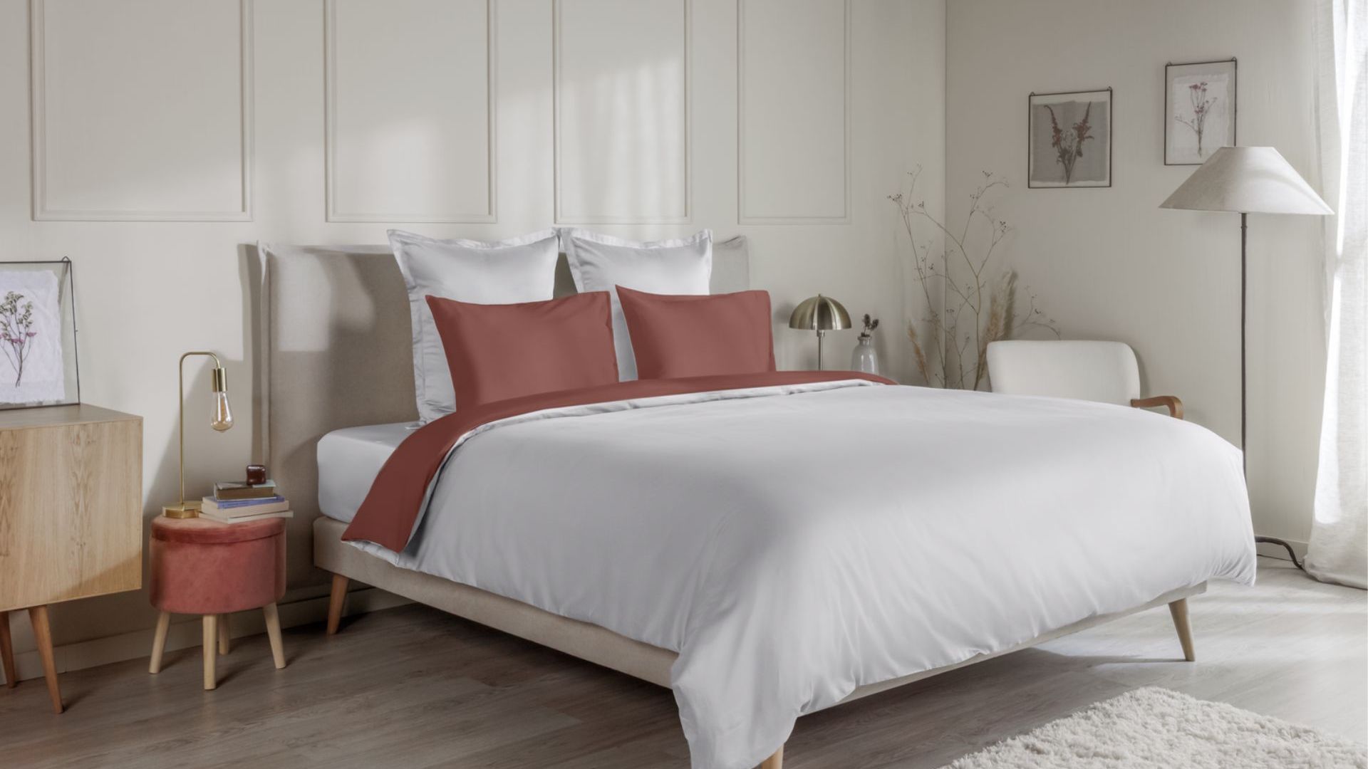 Letto con federe terracotta e coperta coordinata su biancheria bianca, in camera da letto dallo stile accogliente.