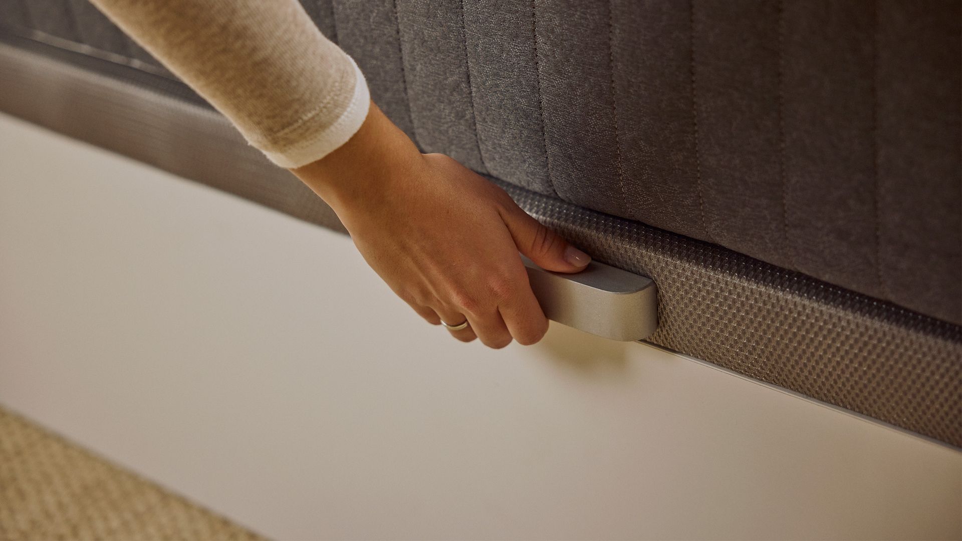 Imagem de uma pessoa a agarrar na pega do tampo do sommier