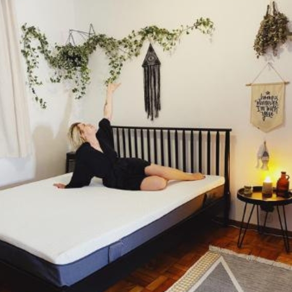 Foto de quarto com moça deitada numa cama, sobre o colchão emma Original.
