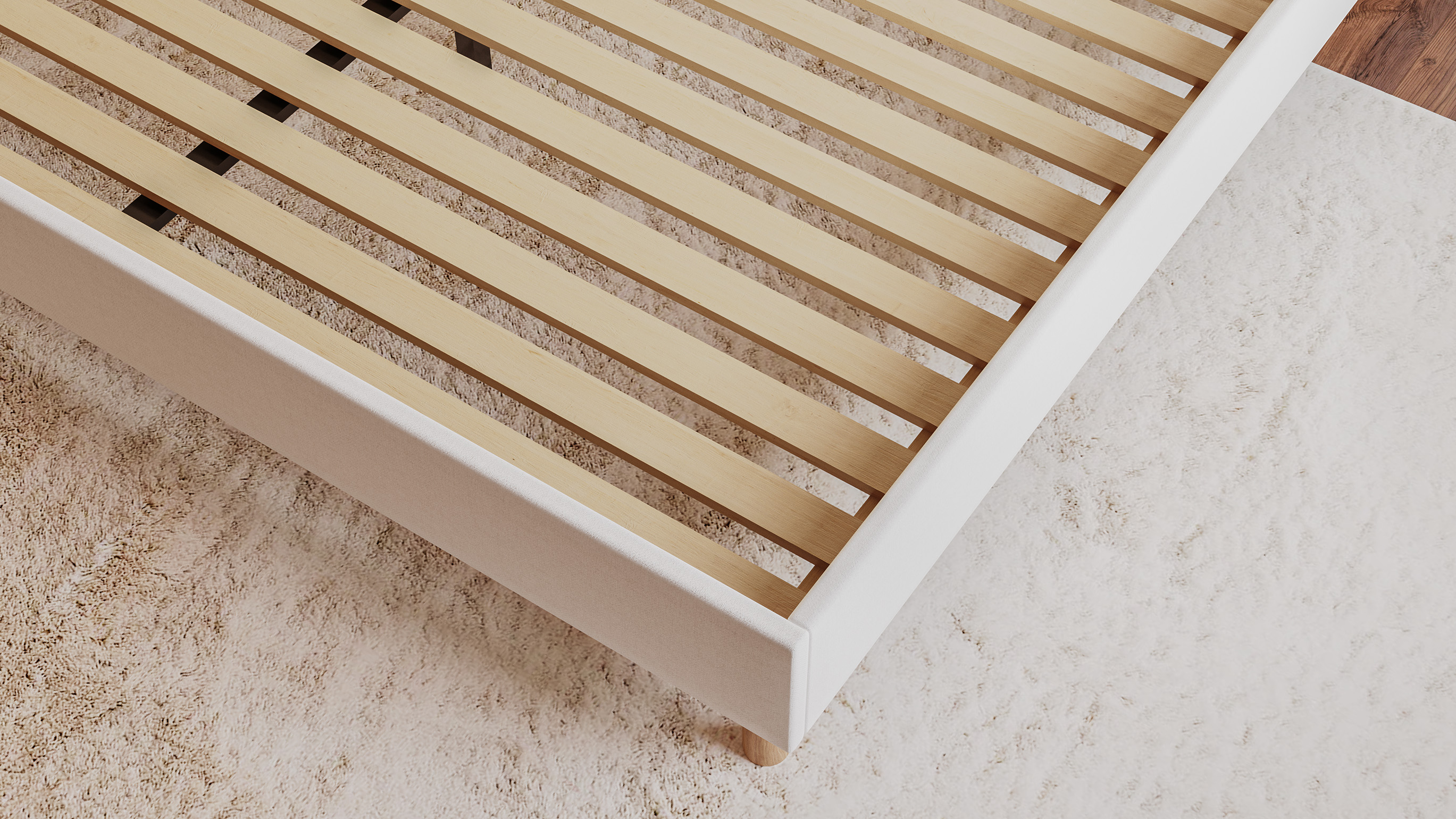 Close-up of the Emma Boxbed in beige showing the wooden slatted base and upholstered frame corner.

