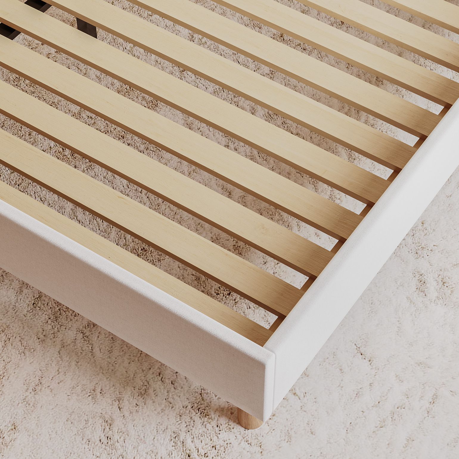 Close-up of the Emma Boxbed in beige showing the wooden slatted base and upholstered frame corner.
