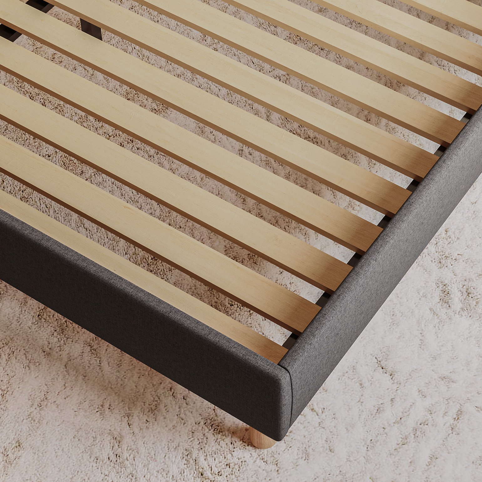 Close-up of the Emma Boxbed in grey showing the wooden slatted base and upholstered frame corner.