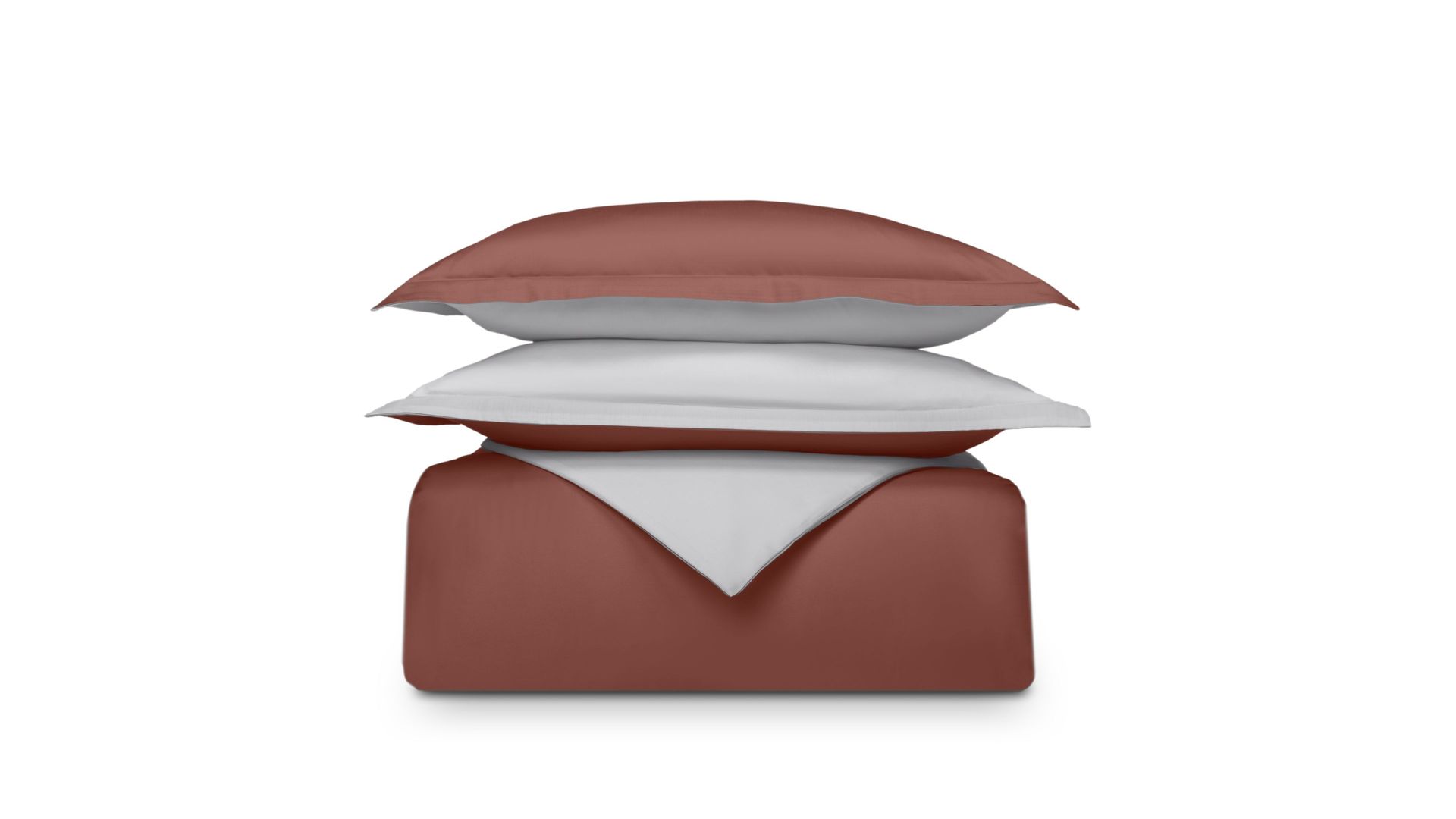 Set di biancheria piegato terracotta e grigio su sfondo bianco, cuscino sopra il piumone.
