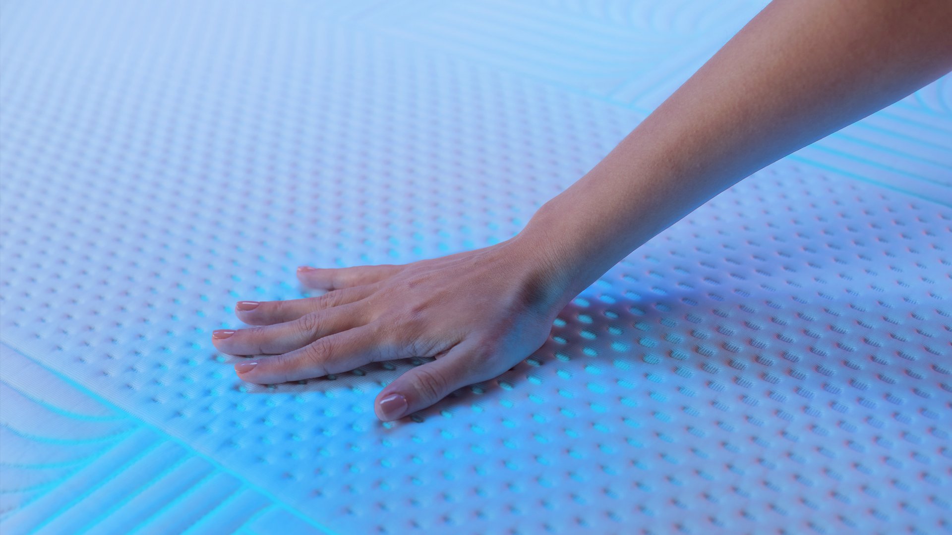 Hand pressing textured mattress cover showing breathable, cushioned surface.