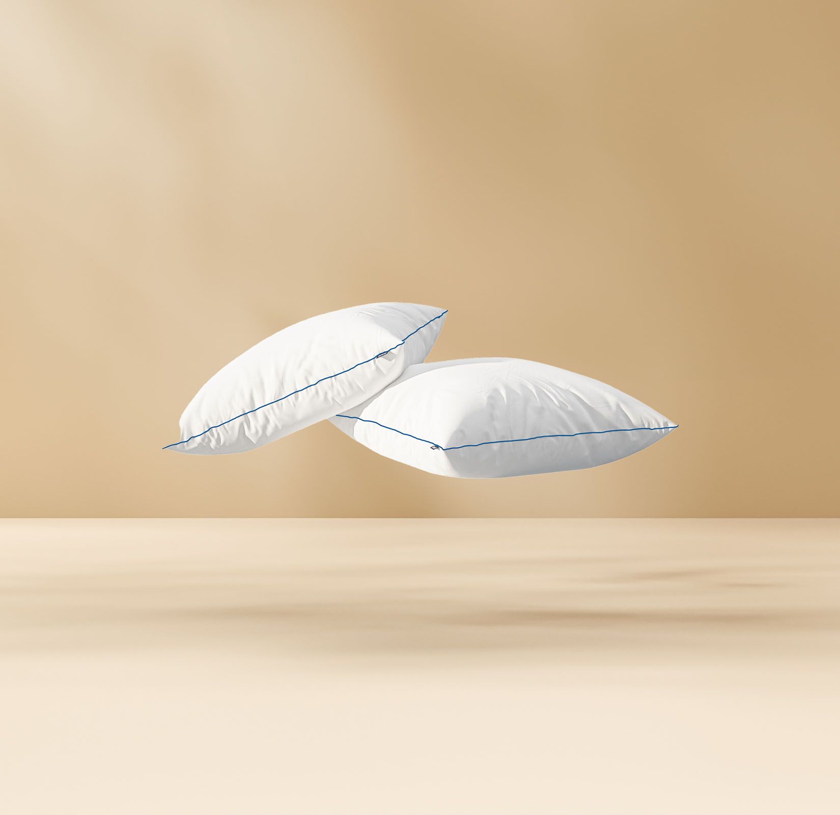 Deux coussins blancs aux bords bleus flottant sur un fond beige, créant une sensation de légèreté et de confort.