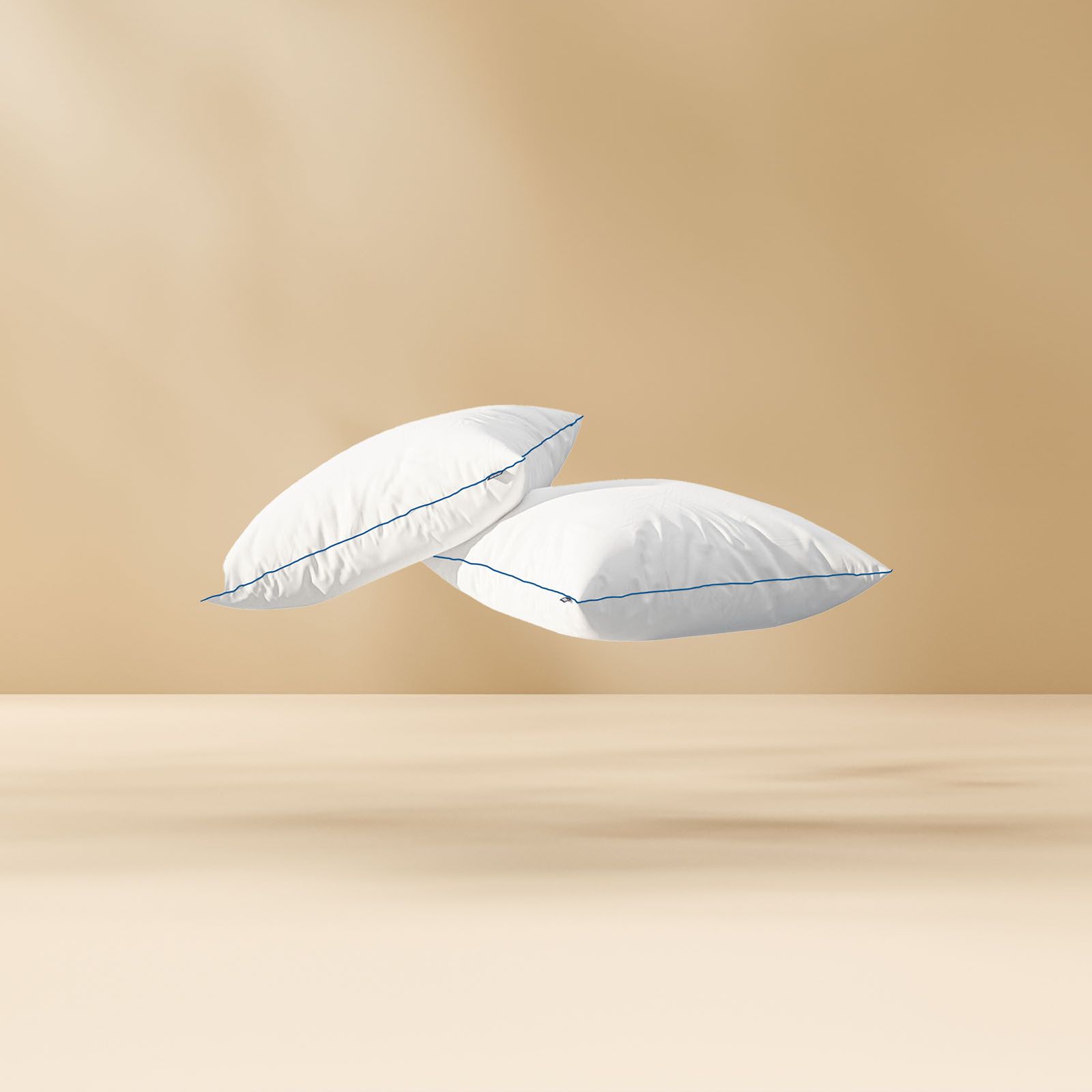 Deux coussins blancs aux bords bleus flottant sur un fond beige, créant une sensation de légèreté et de confort.